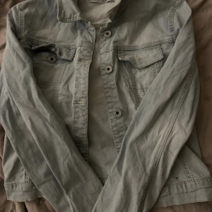 Ljusblå jeansjacka från Vila - Snygg ljusblå jeansjacka från Vila med klassisk krage, bröstfickor med lock och knappar framtill. Vintage