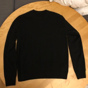 Svart kashmirtröja med rund hals, Uniqlo - En stilren svart tröja i mjuk kashmir med rund hals och långa ärmar. Enkel och klassisk design utan detaljer eller mönster, perfekt för dig som gillar minimalistiskt och bekvämt. Passformen är normal och materialet känns lyxigt mot huden.