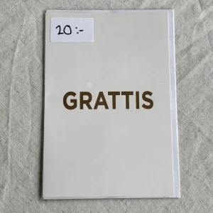 Gratulationskort  - En stilren gratulationskort med texten 'GRATTIS' i stora bokstäver. Medföljer kuvert samt den är kvar i sin ursprungliga förpackning. Insidan består av helt vita blad så plats för mycket text 