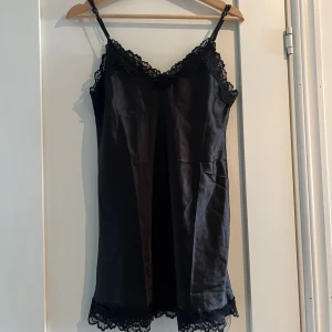 Svart satin nattlinne med spets S - Svart nattlinne i satin med tunna axelband och vacker spetsdetalj längs urringning och fåll. Storlek S, aldrig använd 