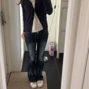 Mörkblå bootcut jeans låg midja - Säljer ett par mörkblå jeans med snygg tvätt och bootcut-modell. Jeansen har låg midja och klassisk femficksdesign. Materialet är jeans och passformen är normal med lätt utsvängda ben. Perfekta för en avslappnad och trendig look. Dem är utrampade längst ner! Helt slutsålda och därav priset!
