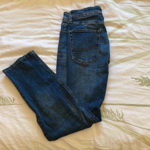 Jack & Jones Skinny Liam jeans blå - Säljer ett par blå skinny jeans från Jack & Jones, modell Liam. Jeansen har klassisk femficksdesign, snygga kontrastsömmar och en smal passform som sitter tajt längs benen. Tillverkade i stretchig denim för extra komfort.