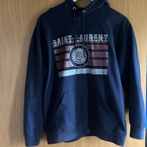 Marinblå Saint Laurent hoodie - Snygg marinblå hoodie från Saint Laurent. Tröjan är i storlek L och har en snygg passform, den är i fint skick och pris kan diskuteras!