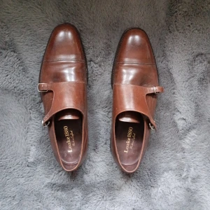 Bruna monk strap-skor från Loake 1880 - Snygga bruna monk strap-skor från Loake 1880, tillverkade i England. Skorna har dubbla spännen i silver,  och är gjorda i skinn. Perfekta för dig som vill ha en klassisk och stilren look. Köpte dom för 4000. Men det blev aldrig att jag använde dom.