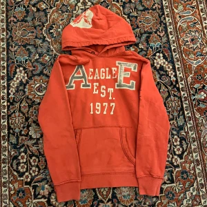 Vintage American eagle hoodie - Otroligt cool vintage American eagle hoodie! Denna har sjuka vintage detaljer som slitning och fade på trycket vid luvan och bröstet. Dessa har blivit väldigt trendiga och efterfrågade senaste därav priset! Mått: Bredd 51cm Längd:61cm