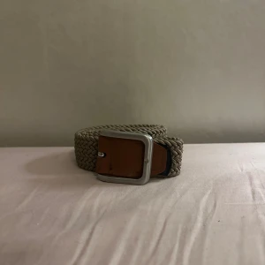 Beige flätat bälte från Jack & Jones - Snyggt beige flätat bälte från Jack & Jones med detaljer i brunt skinn och en silvrig metallspänne. Bältet har en stilren och klassisk look som passar till jeans eller chinos. Perfekt accessoar för att lyfta din outfit.