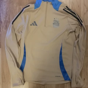 Argentina långärmad träningströja - En skön Argentina tröja som jag växt ur, knappast haft på mig den då jag glömt att jag hade den. Storlek 164 men passar upp mot cirka 170. Köptes för 899kr.