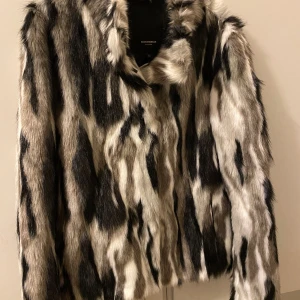 Pälsjacka från Rockandblue, strl 34 - Snygg pälsjacka från Rockandblue i svart, grått och vitt med coolt zebramönster. Jackan har lång ärm och är tillverkad i mjukt pälsmaterial som ger en lyxig känsla. Perfekt för dig som vill sticka ut med en statementjacka.