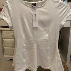 Vit peplum topp från Gina Tricot - Säljer en fräsch vit peplum topp från Gina Tricot i storlek S. Toppen har rund hals, korta ärmar och en snygg utsvängd nederdel som ger en feminin siluett. Materialet är mjuk bomull och toppen är helt enfärgad utan mönster.