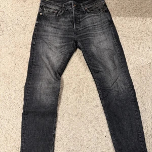 Jeans - Svarta Jack&jones jeans med klassisk femficksdesign och raka ben. Jeansen har en snygg tvättad look med subtila slitningar och är tillverkade i slitstarkt denim. Passar dig som gillar tidlös stil och vill ha ett par jeans med autentisk känsla.