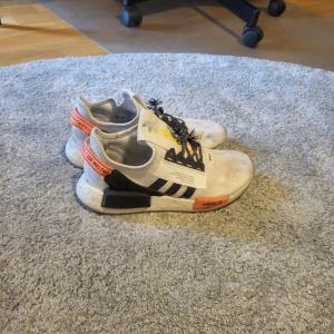 Adidas NMD sneakers vit och orange - Säljer ett par Adidas NMD sneakers i vitt med svarta och orange detaljer. Ja tvättar skorna ordentligt innan frakt!