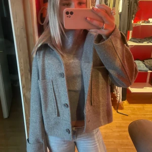 Grå kappa från Kappahl XS - Säljer en grå kappa från Kappahl i storlek XS. Jackan har stora fickor framtill och knäppning med knappar. Materialet är mjukt och känns som ullblandning, perfekt för lager-på-lager. Snygg krage och breda ärmslut. Köpte för 800 men den har fått en liten missfärgning inuti därav priset. Dovk absolut ingen som syns när man var på sig den! 
