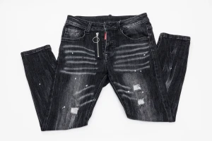 Svarta Dsquared2 jeans med dragkedja - Svarta jeans från Dsquared2 med coolt slitet och blekt utseende, vita färgstänk och patchade detaljer. Unik dragkedja med ring framtill och klassisk Dsquared2-label vid fickan. Jeansen har fem fickor och en snygg svart läderpatch bak.