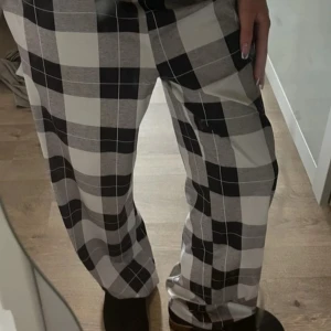 Low waist Svarta och vita rutiga byxor - Snygga byxor med rutigt mönster i svart, vitt och grått. Kan användas som pijamas byxor. Materialet känns mjukt och lätt. 