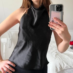 Svart halterneck linnetopp i satin - Helt ny halterneck topp från Zara, enbart provad några gånger. Den har en öppen rygg och är i satin.