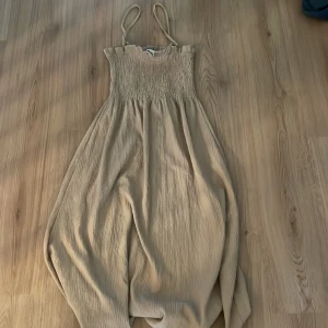 Beige långklänning med smock - Säljer en beige långklänning med smala axelband och smockad överdel. Skulle säga att den passar S eftersom att den är stretchig. Knappt använd skriv om ni har några frågor💕