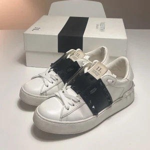 Valentino Garavani Rockstud untitled sneakers - Säljer mina Valentino Garavani Rockstud Untitled skor. Nypris: ca 7000 kr. Använda men i fint skick – se bilder för skick. Storlek: 36.  Kvitto finns, originalkartong och tygpåse medföljer. Klassisk modell i vitt skinn med svarta detaljer och nitar. Supersnygga både till vardag och mer uppklädda outfits. 