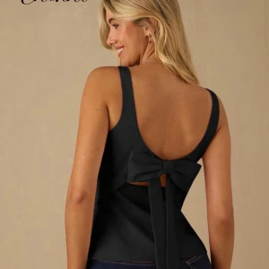 Svart linnetopp med rosett i ryggen - Snygg svart linnetopp med djup urringning i ryggen och stor rosett som detalj. Toppen är ärmlös och har en stilren, enkel design som passar perfekt till jeans eller kjol. Materialet känns mjukt och lätt mot huden.