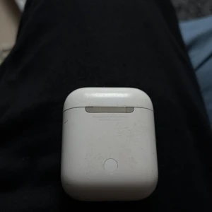 Apple AirPods 2 - Apple AirPods 2 med laddningsetui. Fungerar bra, laddningsindikator lyser. Skick: synligt slitage och repor på både etui och hörlurar, men inga större skador. Perfekt för dig som vill ha trådlösa hörlurar till ett bra pris.