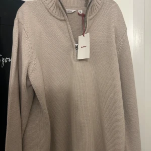 Beige stickad tröja med half zip  - Snygg beige stickad tröja från Dobber med ribbad krage och half zip-dragkedja. Stl M. Helt ny.