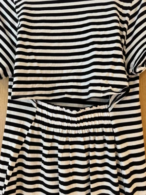 Randig svartvit t-shirtklänning H&M - Säljer en svartvit randig t-shirtklänning från H&M med rund hals och korta ärmar. Klänningen har en loose passform och är gjord i mjuk bomull. Snygg och chill stil med elastisk midja bak för extra komfort. Perfekt för dig som gillar enkel och clean look. Skön t-shirt klänning med öppning i ryggen. 100% bomull. Storlek XS-S. 