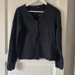 Mörkgrå kofta från 157, storlek S - Mysig mörkgrå kofta från 157 med rund hals och knappar framtill. Koftan är stickad och har långa ärmar samt ribbade muddar vid hals och nederkant. Perfekt för lager-på-lager och chill dagar. Enkel och stilren design som funkar till det mesta.