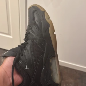 Svarta Nike Air Jordan sneakers - Säljer ett par svarta Nike Air Jordan sneakers med klassisk Jumpman-logga på plösen och Nike Air-detalj på hälen. Skorna har snörning, robust sula med genomskinliga partier och är tillverkade i skinn och textil. Perfekta för dig som gillar streetwear och sportig stil. Perfekt för basket äkta köpte den från Qatar och Scan finns  