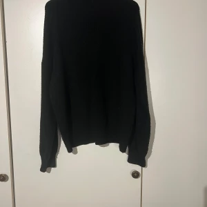 Svart stickad polotröja från AmisuSvart  - Svart stickad polotröja från Amisu i storlek L. Tröjan har ribbad hög hals och långa ärmar med ribbade muddar. Perfekt för dig som gillar enkel och clean stil med lite oversized känsla. Materialet är mjukt och värmande, passar grymt under höst och vinter.