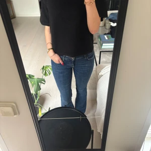 Blå bootcut jeans från Zara, strl 38 - Snygga blå jeans från Zara i storlek 38 med klassisk bootcut passform. Jeansen har normal midja, raka ben och är tillverkade i mjukt denim-material. Fickor både fram och bak, och subtila sömmar för en clean look.