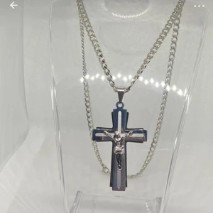 Silverfärgat korshalsband med Jesus - Stilrent halsband i silverfärg med ett stort kors som har en Jesusfigur på framsidan. Kedjan är grov och korshänget har en cool, modern design med flera lager och detaljer. Perfekt för dig som vill ha ett statement-smycke med religiös touch.