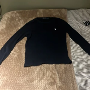 Svart långärmad tröja Polo Ralph Lauren - Marinblå långärmad tröja från Polo Ralph Lauren med klassisk rund hals och liten broderad logga på bröstet. Stilren och enkel design som funkar till många olika looks. Mjukt material som känns skönt mot huden. Passar M på tjejer/kvinnor och S på män/killar