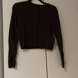 Mörkbrun kofta från 157, XS - Säljer en mörkbrun kofta från 157 i storlek XS. Koftan har rund hals, långa ärmar och knappar hela vägen framtill. Materialet är mjukt och känns som bomull, perfekt för lager på lager. Enkel och stilren design som funkar till många olika looks.