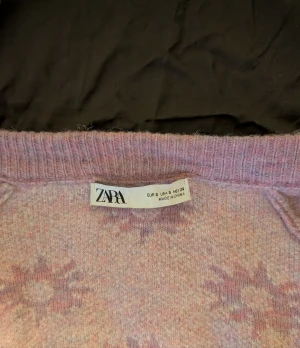 Ljuslila kofta med blommor från Zara!💕💕 - Superfin ljuslila kofta från Zara med vita blommor över hela tröjan. Modell med v-ringning och knappar framtill. Stickad i mjukt material och har långa ärmar. Varm och mysigt material!