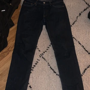 Levi's 511 mörkblå jeans W29 L32 - Snygga Levi's 511 jeans i mörkblå tvätt med klassisk femficksdesign och kontrastsömmar. Slim fit-modell med normal passform och raka ben. Tillverkade i slitstarkt jeanstyg med läderpatch bak i midjan. Perfekt för dig som gillar stilrena och tidlösa jeans. En liten söm på högra fickan har gått upp lite.