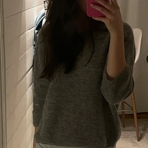 Grå stickad tröja med trekvartsärm - Mysig grå stickad tröja med avslappnad passform och trekvartsärmar. Perfekt för lager-på-lager och chill dagar. Enkel och stilren design som funkar till det mesta.