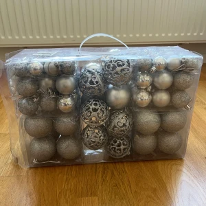 Silver julgranskulor set - Stort set med silverfärgade julgranskulor i olika utföranden, inklusive glittriga och ornamenterade bollar. Levereras i praktisk plastförpackning med handtag. Några kulor har mindre bucklor som går att trycka ut jag har bara inte orkat det, annars i gott skick och redo för dekoration. Är endast använda en jul för 3 årsedan efter det har de stått i förvaring. Är ca 100st och nypris är 400:- 