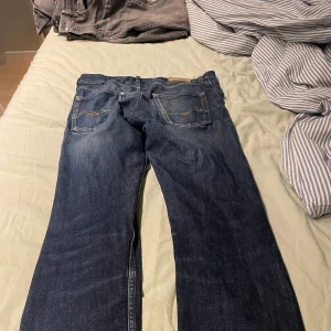 Replay jeans - Snygga mörkblå Levi's 501 jeans med klassisk rak passform och fem fickor. Jeansen har slitningar och kontrastsömmar på bakfickorna samt en brun läderpatch med Levi's-logga i midjan. Perfekta för dig som gillar tidlös denimstil.
