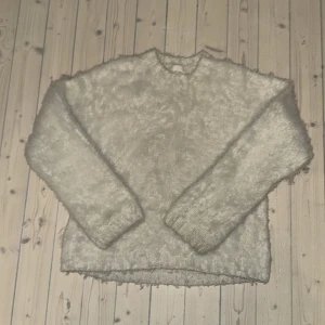 Ljus fluffig stickad tröja från H&M - Supermysig ljusbeige stickad tröja från H&M i storlek XS. Tröjan har lång ärm och är gjord i ett fluffigt material som känns extra mjukt och varmt. Perfekt för dig som gillar chill och comfy vibes under höst och vinter. köpte den för 500.