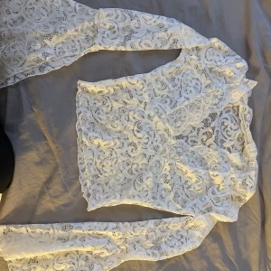 Vit spets topp V-ringat och långa ärmar - Säljes pga fel storlek! Org pris 400 Säljer en superfin vit spets topp med V-ringat och långa ärmar. Blusen är genombruten med vackert spetsmönster och har en feminin v-ringning. Perfekt för dig som gillar romantisk och trendig stil. 