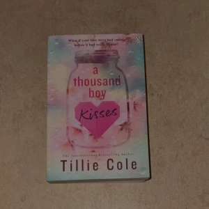 A Thousand Boy Kisses - En känslosam och romantisk bok som fångar hjärtat! Perfekt för dig som älskar starka kärlekshistorier och vill drömma dig bort. Omslaget är färgglatt och lockande, och boken är skriven av den internationella bästsäljaren Tillie Cole.