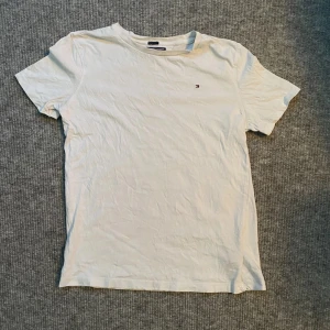 Tommy Hilfiger T-shirt  - Säljer en vit Tommy Hilfiger T-shirt i storlek 164. Använt skick men inga skador.