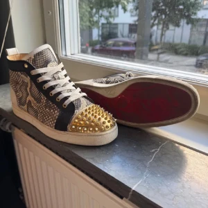 Christian Louboutin sneakers med nitar - Säljer min killes Louboutin skor med ormskin på sidan och guld nitar❤️ Skriv om intresserad