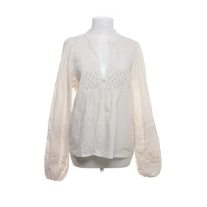 Blus med spets från Vila - Säljer en blus från Vila med v-ringad hals och dekorativa spetsdetaljer både vid halsringningen och på de långa puffärmarna. Blusen har en avslappnad passform och är tillverkad i mjuk bomull. Perfekt för dig som gillar boho-vibe och snygga detaljer.