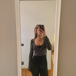 Svartvit omlott croppad topp - Säljer en svartvit croppad topp med omlott-skärning och v-ringning. Toppen har lång ärm och ett melerat mönster. Sitter tight och är perfekt att styla med höga jeans eller kjol. Materialet känns mjukt och stretchigt.