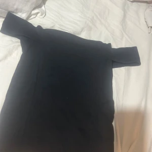 Svart offshoulder topp Cubus M - Svart topp från Cubus storlek M. Snygg offshoulder-modell med raka linjer och enkel design. Tillverkad i mjukt bomullsmaterial som känns skönt mot huden. Perfekt för dig som gillar minimalistisk stil och vill ha en topp som sticker ut med sin axelbandslösa look.