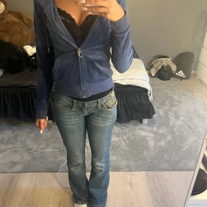 Blå velour hoodie från Juicy Couture - Säljer en mörkblå hoodie från Juicy Couture i mjuk velour med dragkedja framtill och snörning vid huvan. Tröjan har långa ärmar, ribbade muddar och en klassisk Juicy Couture-logga broderad på bröstet. Perfekt för en chill och snygg look. Jag använder xs i tröjor men denna storleken passar jätte bra 