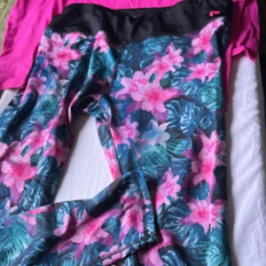 Blommiga träningsleggings från H&M Sport - Snygga träningsleggings från H&M Sport i storlek XL med blommigt mönster i rosa och blå toner samt svart midja. Perfekta för gymmet eller löprundan, med stretchigt syntetmaterial som sitter skönt och följer kroppens rörelser.