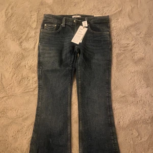 Ultra low bootcut jeans från Gina Tricot - Snygga ultra low bootcut jeans i djupblå tvätt från Gina Tricot, modell Perfect Jeans. Låg midja och klassisk bootcut passform med coola kontrastsömmar på bakfickorna. Materialet är jeans med stretch för extra komfort.