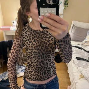 Leopardmönstrad meshtröja från Gina Tricot - Säljer en tight långärmad meshtröja från Gina Tricot med leopardmönster i beige och bruna toner. Tröjan har rund halsringning och är figurnära i modellen, perfekt att styla med jeans eller kjol för en cool look💗