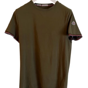 Moncler T-Shirt  - Moncler slim fit T-shirt oliv grön. Storlek L. Passar M. Skick 9/10. Pris 990! Finns att köpa på våran hemsida, Fashionels.com 